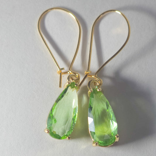 Gros plan sur pendentifs en verre vert des boucles d’oreilles Aube verte, plaqué or