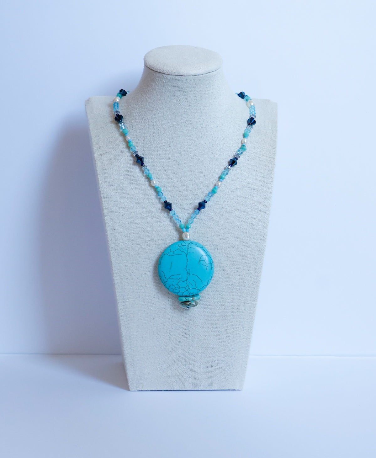 Collier composé d'une grande turquoise centrale, de perles d'eau douce et d'un dégradé de cristaux bleus.